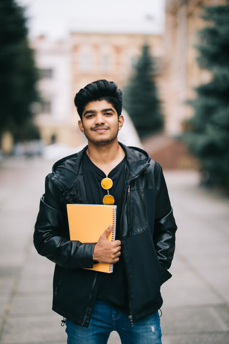 handsome-young-indian-student-man-holding-notebooks-while-standing-street_231208-2771