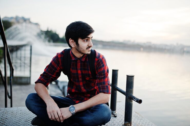 young-indian-student-man-checkered-shirt-jeans-with-backpack-posed-evening-city-against-fountains_627829-2737